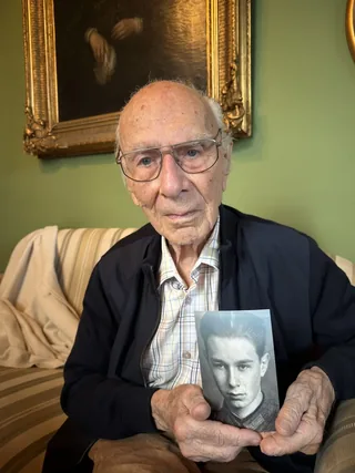 Dieter von Levetzow holding a photograph of himself as a young man.