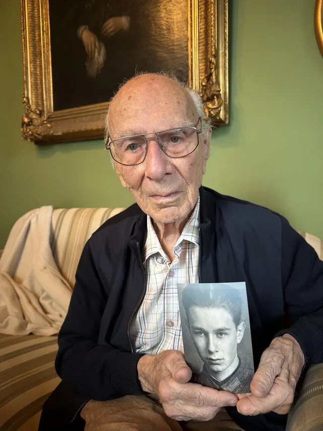 Dieter von Levetzow holding a photograph of himself as a young man.