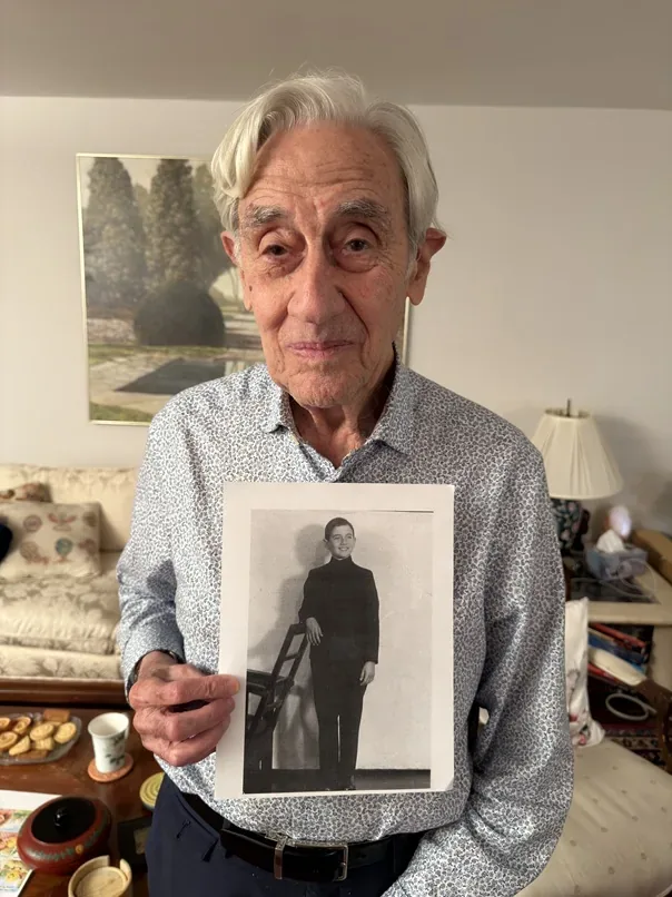 Elly Gotz holding a photograph of himself as a young man.