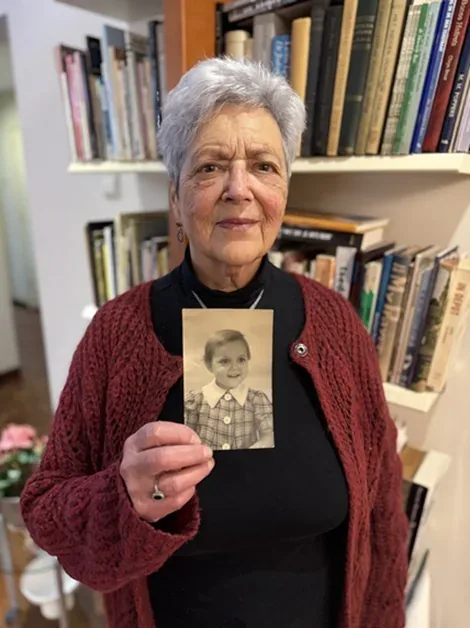 Esther Boas holding a photograph of herself as a young child.