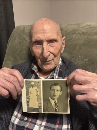 Georges Goguin holding photographs from 1936 and 1946.