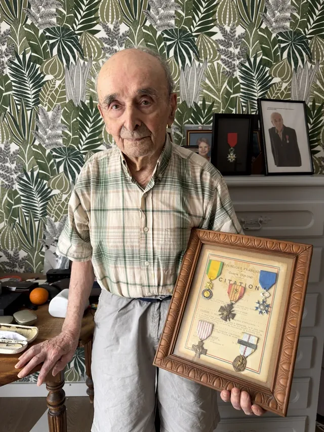 Germain Malaterre holding his framed military decorations and citation.