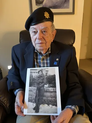 Harry Arnstein holding a photograph of himself during his military service.