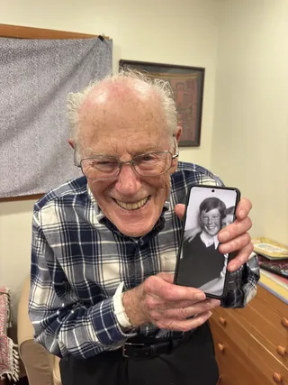 Jan Roček holding a phone displaying a childhood photograph.