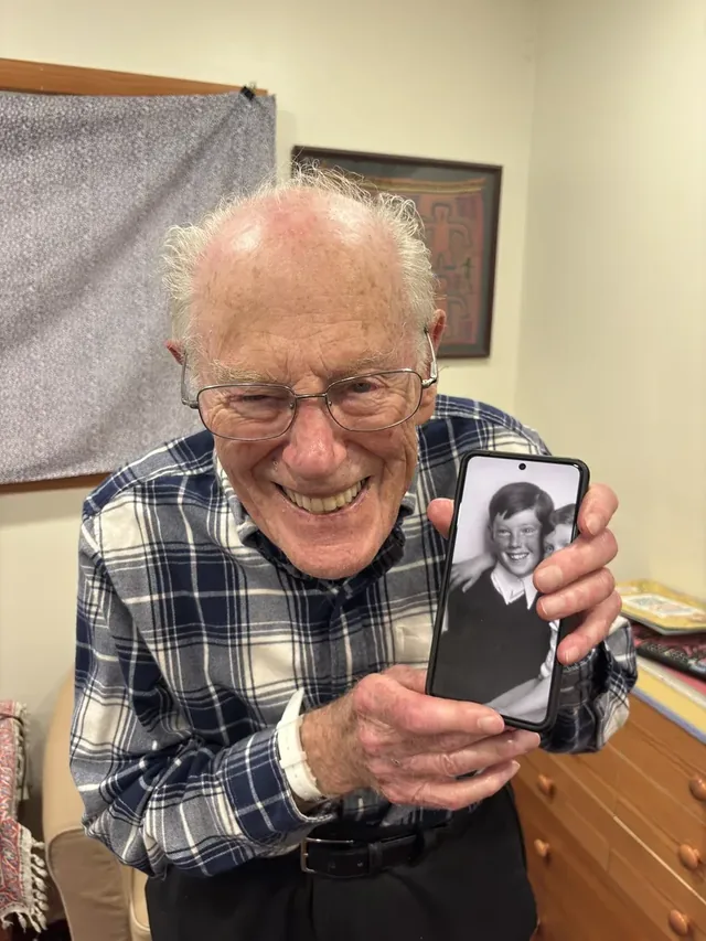 Jan Roček holding a phone displaying a childhood photograph.