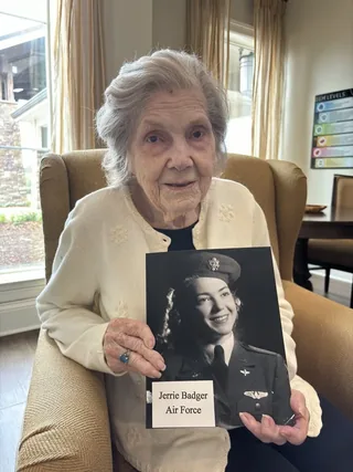 Jerrie Badger holding a photograph of herself in uniform.