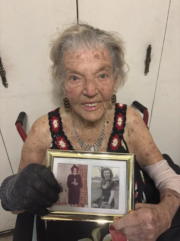 Lena Goren holding framed photographs from her younger years.