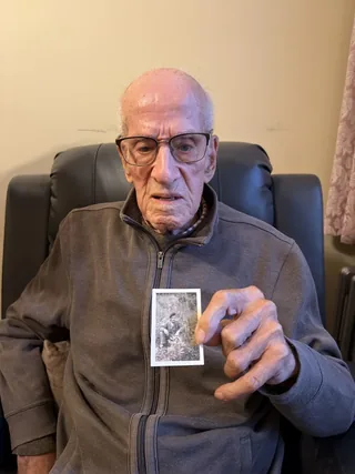 Léon Moyen holding a photograph from his military service.