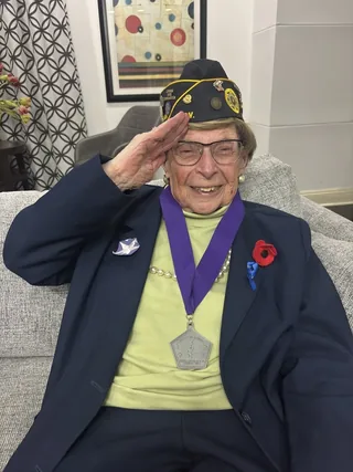 May Brill saluting while wearing her veterans’ service cap.