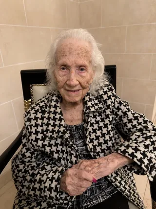 Renée Firestone seated in a patterned coat.