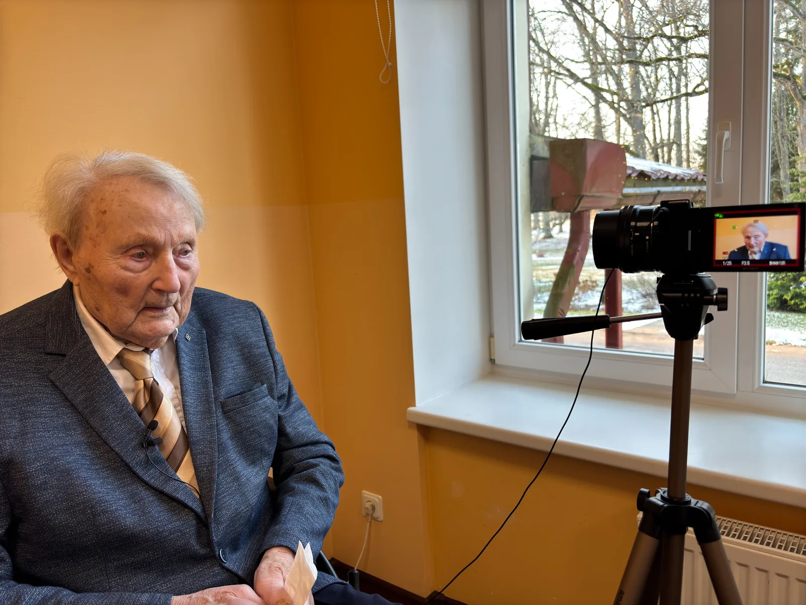 Uldis Maksiņš during a recorded interview, seated beside a camera.